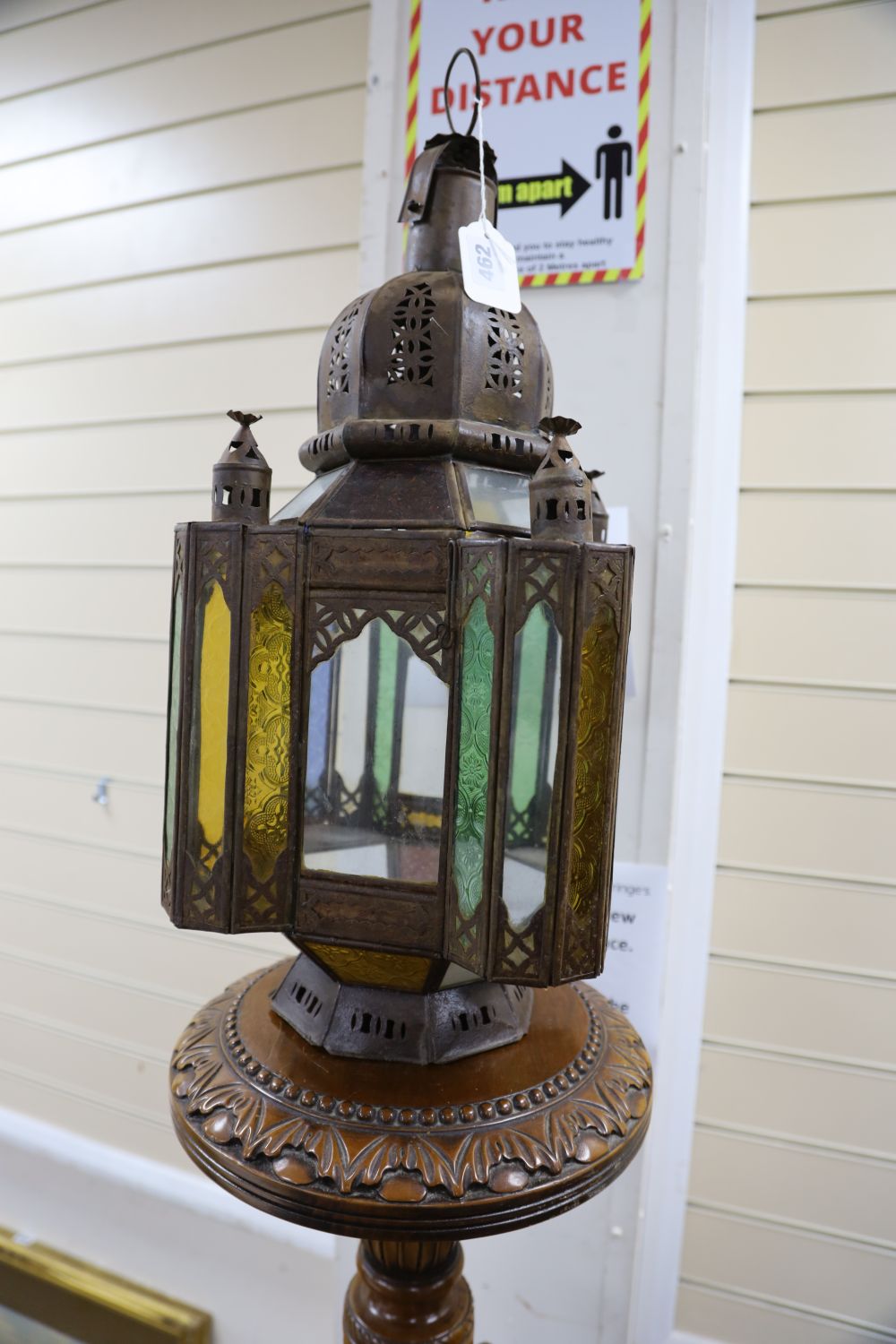 A pierced metal lantern with coloured glass panes, on carved walnut triform pedestal, 206cm overall